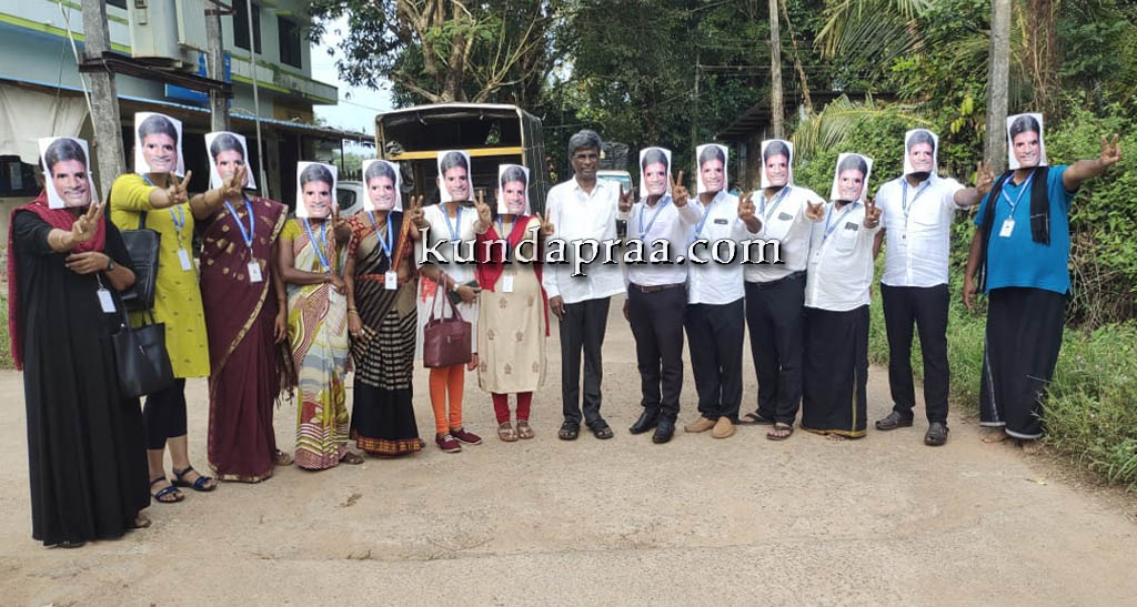 ಅಭ್ಯರ್ಥಿ ಕೋಟ ಶ್ರೀನಿವಾಸ ಪೂಜಾರಿ ಮುಖವಾಡ ಧರಿಸಿ ಮತಗಟ್ಟೆಗೆ ತೆರಳಿದ ಪಂಚಾಯತ್ ಸದಸ್ಯರು